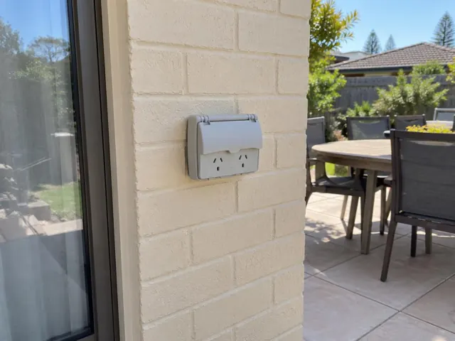Outdoor double power point on a cream brick exterior wall beside a patio in Bateau Bay
