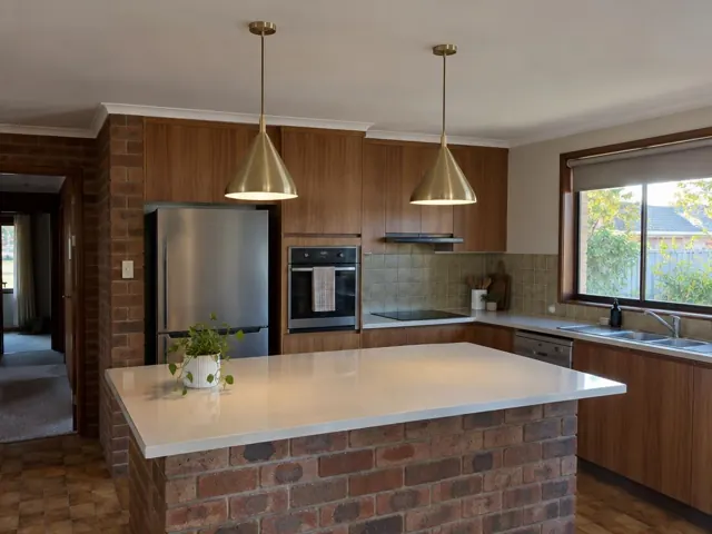 Modern kitchen with two brass pendant lights over a brick island in Bateau Bay